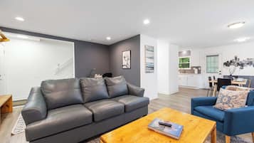 Un salon moderne avec un canapé en cuir gris, une table basse en bois et un fauteuil bleu.