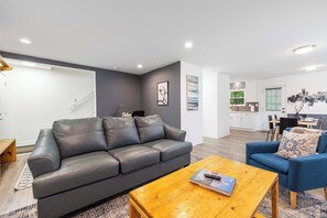 Ein modernes Wohnzimmer mit einem grauen Ledersofa, einem Holztisch und einem blauen Sessel.