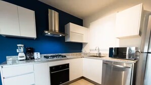 Una cocina moderna con armarios blancos, estufa integrada, microondas y lavavajillas.