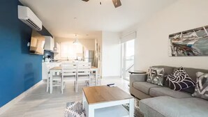 Una sala de estar moderna con un sofá gris, una mesa de centro de madera y un ventilador de techo.