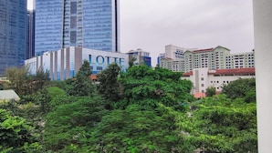 A hotel with a modern glass facade, surrounded by lush greenery and other buildings. - Xumi Motel (Hanoi)