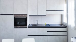 Ett modernt kök med grå skåp, en svart bänkskiva och en diskho i rostfritt stål.