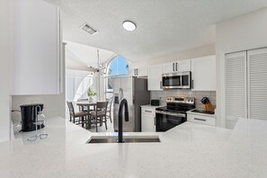 A modern kitchen with white cabinetry, stainless steel appliances, and a central island with a sink. - Family-Friendly 4BR Villa with Pool, Games Room, Minutes from Disney (Kissimmee)