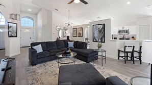 En moderne stue med en hjørnesofa, et sofabord og et spiseområde med stole.
