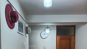 A hallway with a wooden floor, a wooden door, a wall clock, and a telephone. - Eli's home (Cusco)