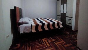 A bedroom with a bed, a wardrobe, and a patterned floor. - Eli's home (Cusco)