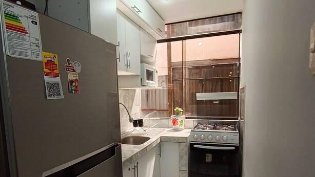 A compact kitchen with a refrigerator, stove, oven, and a microwave. - Eli's home (Cusco)
