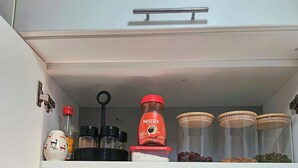 A kitchen cabinet with shelves containing various kitchen items like jars, a coffee maker, and cookware. - Eli's home (Cusco)