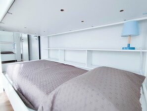 A bedroom with a bunk bed, a white headboard, a bedside table, a lamp, and a ceiling with recessed lighting. - Comfortable Apartment With Pool (Cavallino-Treporti)