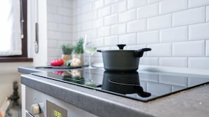A kitchen with a stove, a pot, and some vegetables on the counter. - Italianway Easy - Leoncavallo 45 (Milan)