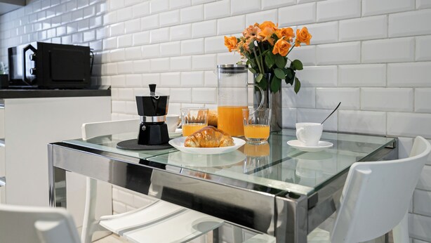 A breakfast table with a coffee maker, croissant, orange juice, and flowers. - Italianway Easy - Leoncavallo 45 (Milan)