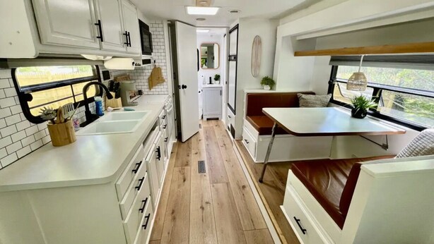 Una cocina compacta con armarios blancos, una isla central y un ventanal con vistas.