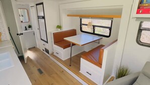 Interior compacto de una autocaravana con kitchenette, comedor y zona de estar.