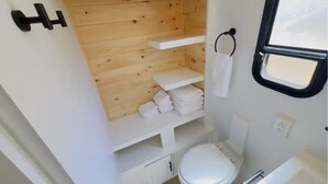 Un baño pequeño con tocador de madera, inodoro y ventana.