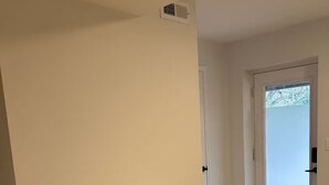 Ein Zimmer mit einem weißen Tisch, zwei Holzstühlen, einer weißen Tür und Blick auf eine verschneite Landschaft durch ein Fenster.