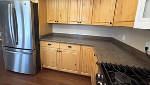 Una cocina con armarios de madera, un refrigerador de acero inoxidable y una estufa a gas.
