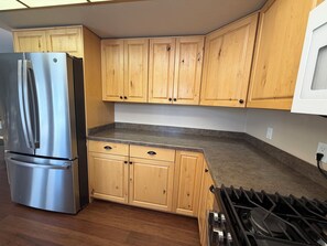 A kitchen with wooden cabinets, a stainless steel refrigerator, and a gas stove. - 5-bedrooms, Tons of Outdoor Space, Central Location! (Kalispell)