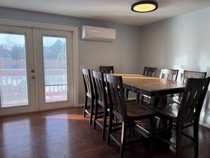 A dining room with a wooden table and chairs, an air conditioning unit, and a view through a glass door. - 5-bedrooms, Tons of Outdoor Space, Central Location! (Kalispell)