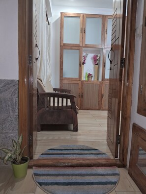 Une pièce comprenant un canapé, un meuble en bois, une plante en pot et un tapis à rayures.