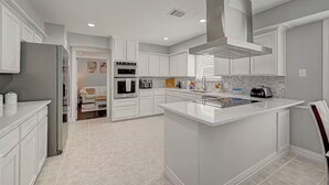 A modern kitchen with white cabinetry, stainless steel appliances, and a central island. - Paradise Garden Resort And Spa (Houston)