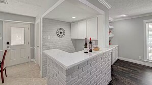 A kitchen with white brick walls, a white countertop, and a clock on the wall. - Paradise Garden Resort And Spa (Houston)