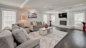 A spacious living room with a grey sofa set, a white coffee table, and a fireplace. - Paradise Garden Resort And Spa (Houston)