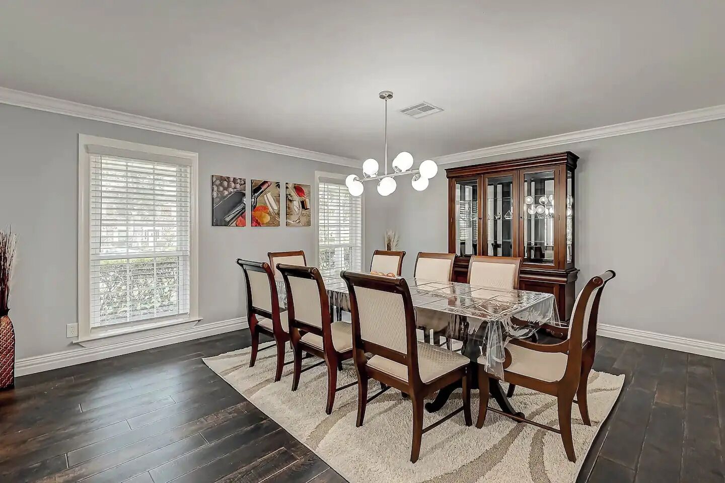 A dining room with a wooden table and chairs, a chandelier, and a large mirror.