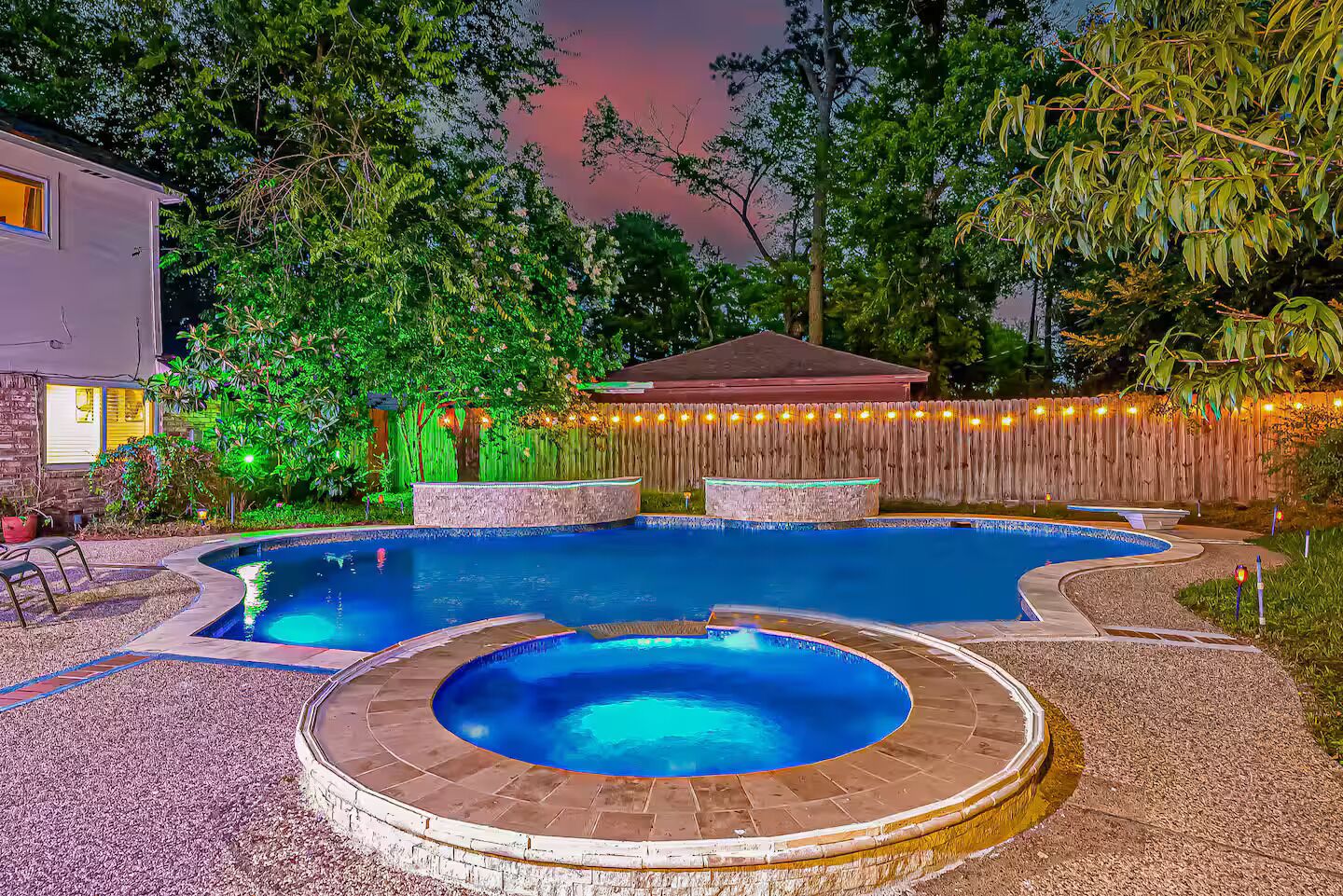 A backyard with a swimming pool, a hot tub, and a wooden deck.