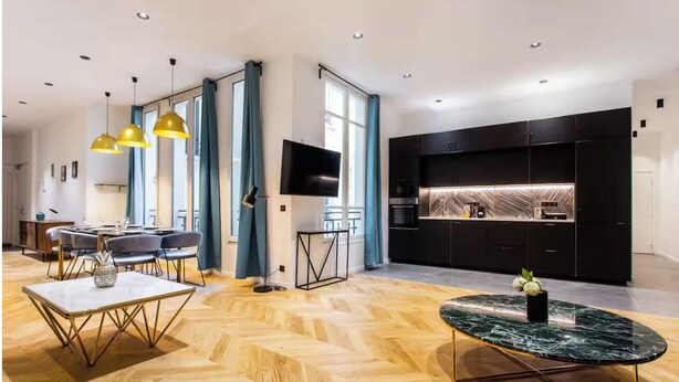 A modern living room with a herringbone wood floor, a round marble coffee table, and a dining area with a white table and chairs. - HOTEL BOETIE - CHAMPS ELYSEES  (Paris)