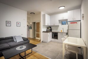 Een moderne keuken met witte kastjes, een koelkast en een eethoek met een tafel en stoelen.