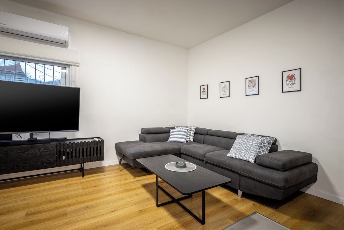 Uma sala de estar moderna com sofá seccional, televisão de tela plana, mesa de centro e radiador.