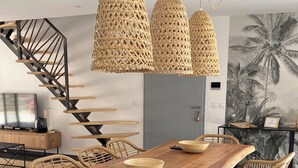 Et moderne spiseområde med et træbord, fletstole og hængende rattanlamper.