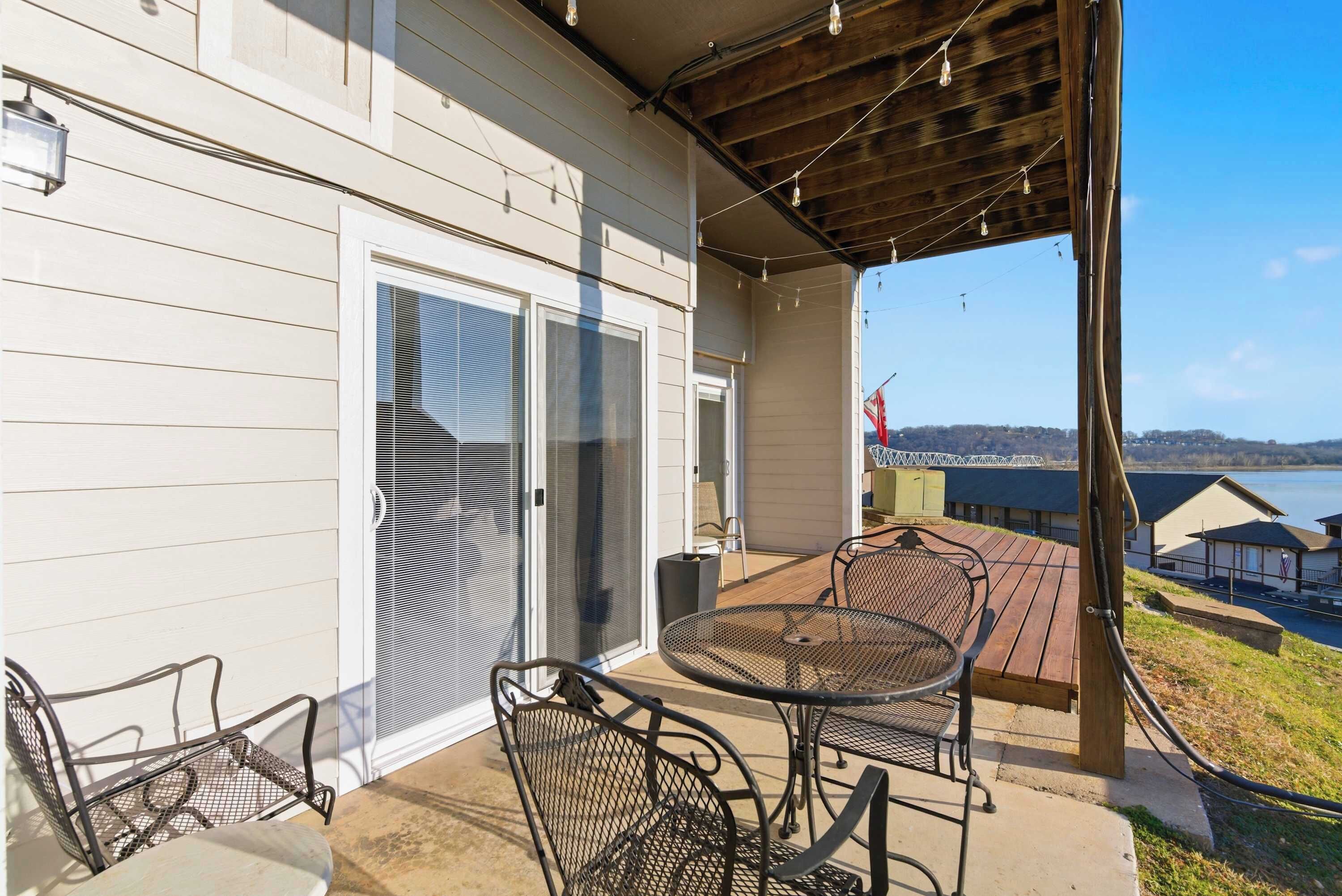 A covered patio with a table and chairs, a sliding glass door, and a view of a lake.