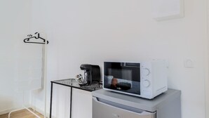Uma cozinha compacta com micro-ondas, cafeteira e pequena geladeira.