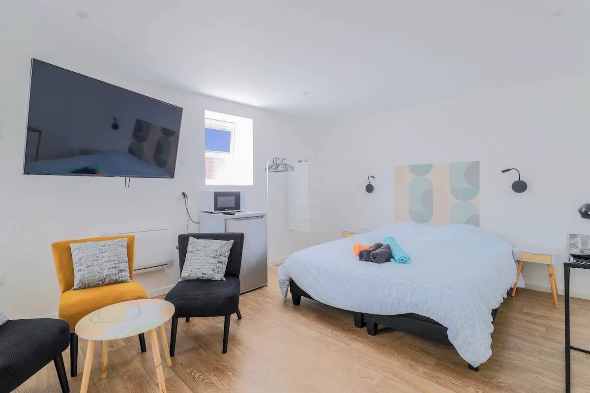 Un dormitorio moderno con una cama grande, un televisor de pantalla plana en la pared, un escritorio pequeño y una silla.