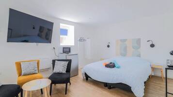 Un dormitorio moderno con una cama grande, un televisor de pantalla plana en la pared, un escritorio pequeño y una silla.