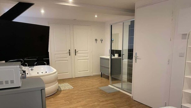Een moderne slaapkamer met een groot bed, een badkuip en een inloopkast.