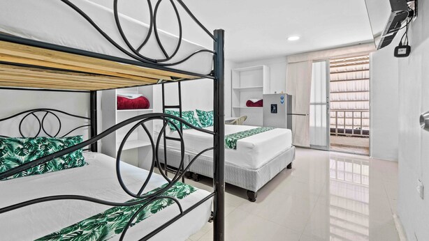Habitación con literas, una cama individual, escritorio, refrigerador pequeño y ventana con persianas.