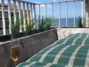 A balcony with a wooden railing, a glass of drink, and a view of the ocean. - Blue Moon (Sea-Senses) (Koksijde)