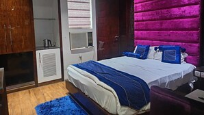 A bedroom with a bed, a wardrobe, a radiator, and a window with blinds.