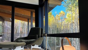 Ein modernes Zimmer mit großem Fenster und Blick auf einen Wald.
