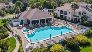 Ein Wohnkomplex mit Schwimmbad, Liegestühlen und überdachter Terrasse.
