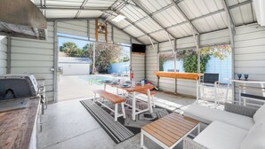 A covered patio area with a barbecue grill, a pool table, and outdoor seating. - Luxury Beach Retreat Pool Walk to Beach Sleeps 12 (Melbourne Beach)