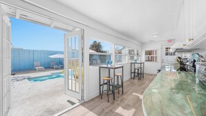 A spacious kitchen with a large island, bar area, and a view of a swimming pool. - Luxury Beach Retreat Pool Walk to Beach Sleeps 12 (Melbourne Beach)