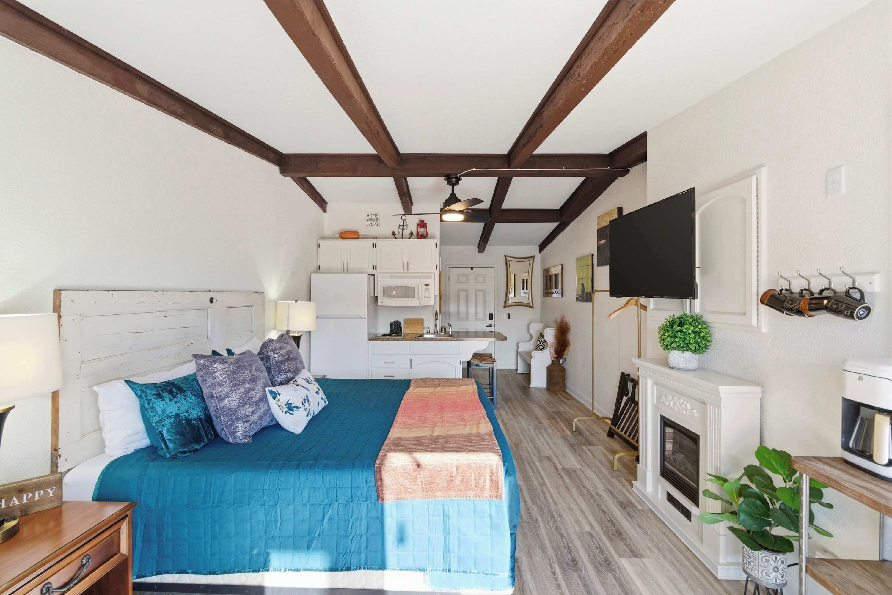 Un dormitorio con cama, escritorio, chimenea y televisión.