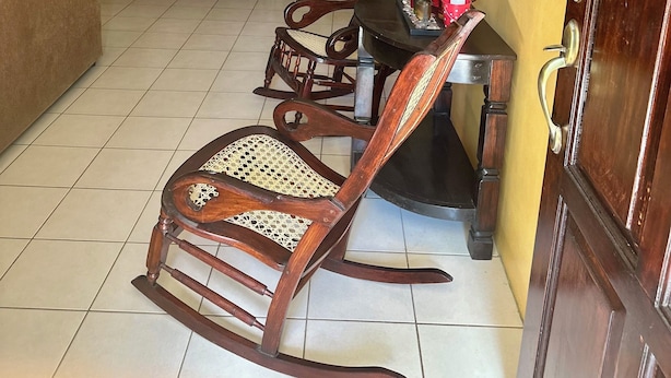 Ein Essbereich mit Holzzmöbeln, einem Esstisch, Stühlen und einer Couch.