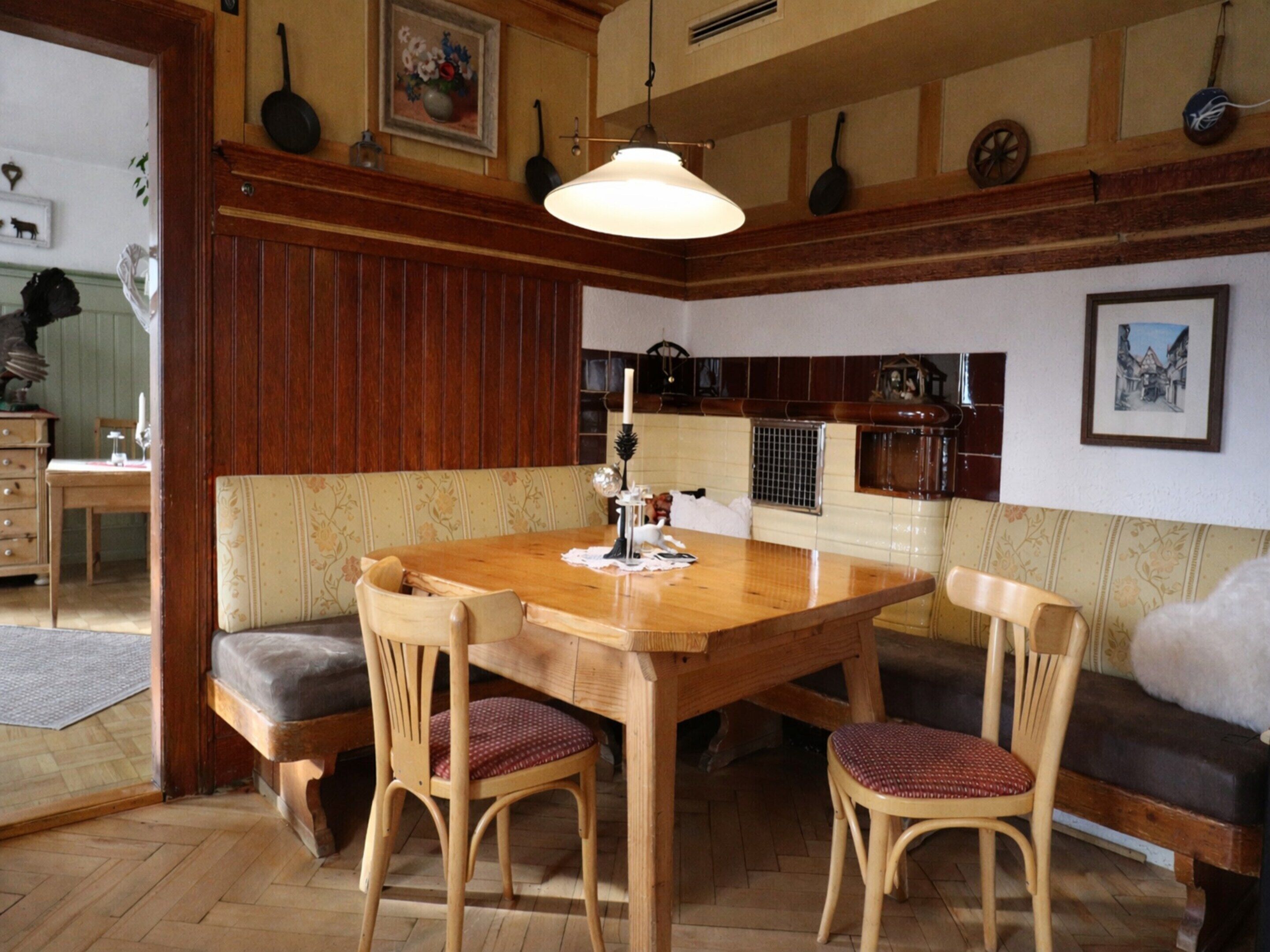 A cozy dining area with a wooden table and chairs, a bench, and a hanging light fixture.