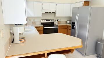A compact kitchen with a built-in oven, a refrigerator, and a coffee maker.