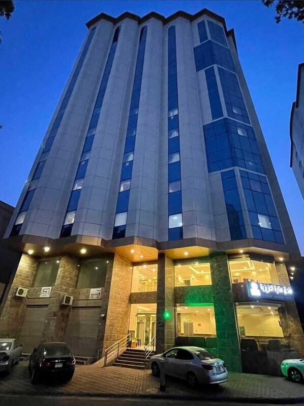 A tall, modern building with a glass facade and a prominent entrance. - Manarat Al Aziziyah Hotel (Makkah)