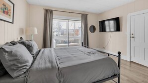 Une chambre à coucher avec un lit, une télévision, une fenêtre et une porte.